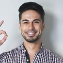 Man with dark hair and stubble smiles, making an